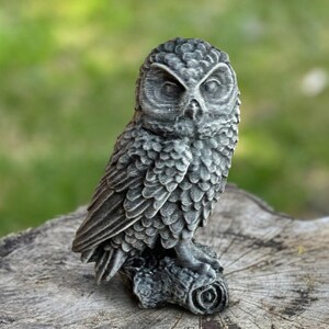 May include: A detailed, gray owl figurine perched on a weathered tree stump. The owl has textured feathers and a focused gaze. The sculpture is a decorative item, suitable for home decor or as a gift.