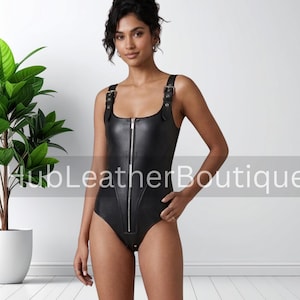 May include: Black leather bodysuit with a square neckline, shoulder straps with buckles, and a full-length zipper. The one-piece garment is form-fitting and has a low-cut back. The image includes the text "HubLeatherBoutique".