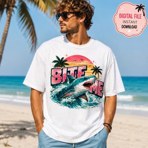 May include: A white short-sleeve t-shirt featuring a graphic print of a shark emerging from ocean waves. The design includes a sunset, palm trees, and the text BITE ME in bold pink letters. A pink badge in the corner reads DIGITAL FILE INSTANT DOWNLOAD.