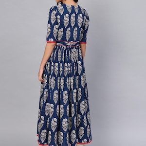May include: A navy blue dress with a white floral pattern. The dress has short sleeves, a round neckline, and a red trim along the sleeves and waist. The dress is floor-length and has a pleated skirt.