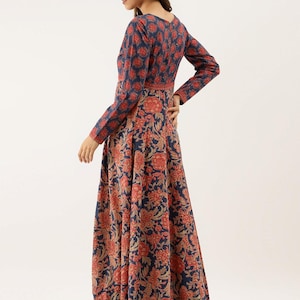 Puede incluir: Un vestido largo de manga larga con un estampado floral en tonos azul marino, rojo y dorado. El vestido presenta un escote en V y un corpi&ntilde;o ajustado que fluye hacia una falda acampanada. El estampado floral es consistente en todo el vestido.