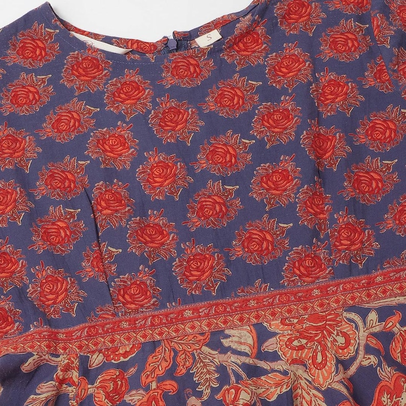 Puede incluir: Vestido azul con un estampado floral de rosas rojas. El vestido tiene un cuello redondo y un borde detallado con un dise&ntilde;o floral. La tela parece suave y ligera, adecuada para climas c&aacute;lidos. Talla 'S'.