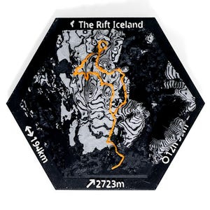 May include: A hexagonal black plaque featuring a 3D topographic map of The Rift Iceland. The map displays black and white contour lines with a prominent orange trail path. Text includes The Rift Iceland, 19.4km, and 2723m printed on the edges.