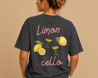 Puede incluir: Camiseta gris oscuro con un diseño de temática de limón. La parte posterior de la camiseta presenta las palabras "Limon cello" en rosa, junto con ilustraciones de limones y copas de cóctel. La camiseta está hecha de un material suave y cómodo.