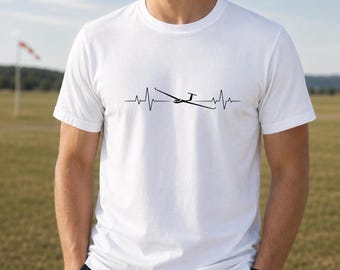 Puede incluir: Una camiseta blanca de manga corta con un estampado gráfico negro en el pecho. El diseño consiste en un patrón de línea de latido del corazón que incorpora la silueta de un planeador en el centro de la onda del electrocardiograma.