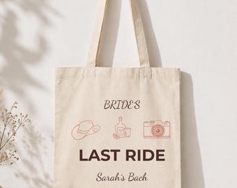 Puede incluir: Una bolsa de mano de lona beige con las palabras "BRIDES LAST RIDE Sarah's Bach" en texto negro y marrón. La bolsa presenta dibujos lineales de un sombrero de vaquero, una botella con dos chupitos y una cámara.