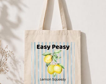 Puede incluir: Bolso tote de lona beige con las palabras "Easy Peasy" en negro sobre una ilustración de limones. Debajo de los limones, el texto dice "Lemon Squeezy". El fondo presenta rayas verticales de color azul claro.
