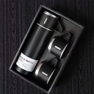 May include: A black vacuum bottle set with two matching cups, presented in a dark gray box. The bottle has a white label with text. The set is designed for travel and outdoor use.