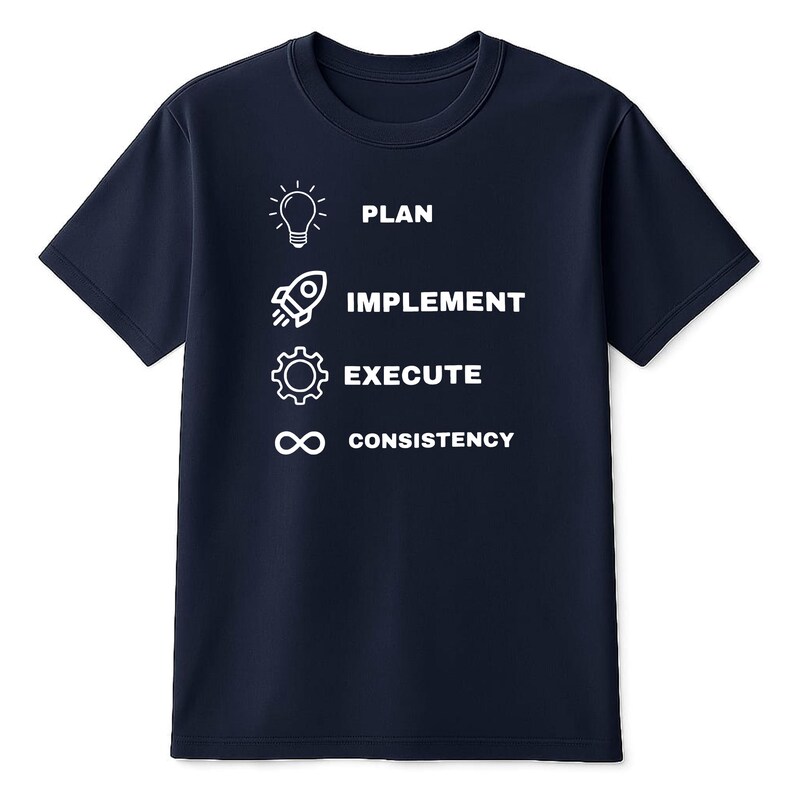 May include: A navy blue short-sleeved t-shirt featuring a white graphic design with four rows. Each row contains an icon and text: a lightbulb with the word PLAN, a rocket with IMPLEMENT, a gear with EXECUTE, and an infinity symbol with CONSISTENCY.