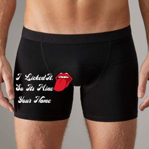 Könnte beinhalten: Schwarze Boxershorts mit dem weißen Text "I Licked It, So Its Mine Your Name". Auf der Vorderseite befindet sich eine rote Cartoon-Zunge. Die Shorts sind aus weichem Material.