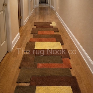 Könnte beinhalten: Ein Flurläufer-Teppich mit einem geometrischen Muster in Braun-, Orange- und Gelbtönen. Der Teppich besteht aus einem weichen, strukturierten Material und liegt auf einem Holzboden. Der Text "The rug Nook co" ist sichtbar.