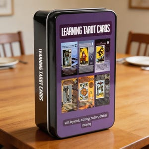 May include: A black metal box with a purple label that reads "LEARNING TAROT CARDS." The box displays several tarot card images and text, including "with keywords, astrology, zodiacs, chakras meaning."