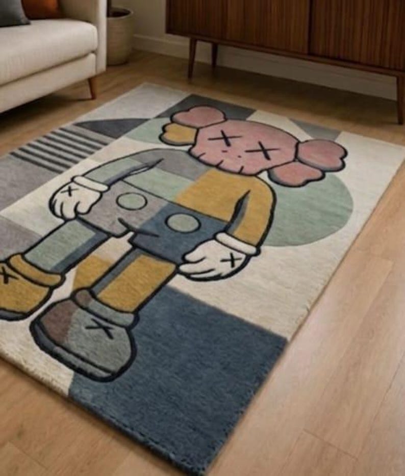 May include: A rectangular rug with a cartoon character design in grey, yellow, blue, and pink. The rug has a geometric pattern and is placed on a wooden floor.