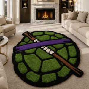 May include: A circular rug shaped like a turtle shell with a green and black segmented pattern. A brown staff with a purple mask tied around it is positioned diagonally across the center of the shell, featuring white accents on the staff.