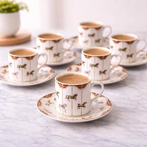 Könnte beinhalten: Eine weiße Keramik-Tasse mit schwarzem Henkel und dem Text "But First, Coffee" in handschriftlichem Stil. Die Tasse steht auf einer weißen Oberfläche. Die Tasse ist etwa 10 cm hoch.