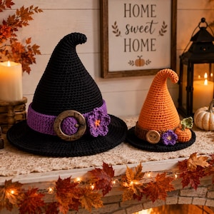 May include: Two crocheted witch hats, one large black hat with a purple band and a wooden buckle, and one smaller orange hat with a brown band, a wooden button, and a small crocheted pumpkin. Both hats feature a pointed, curved top design.