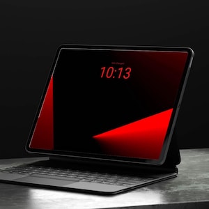 May include: A black tablet computer with a thin bezel and a dark screen displaying the red digital time 10:13. The tablet is attached to a black keyboard case with a trackpad, featuring a red geometric graphic on the display screen.