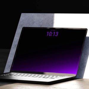 Könnte beinhalten: Ein schwarzer Laptop mit einem dunklen Bildschirm, der den violetten Text 10:13 anzeigt. Das Gerät verfügt über einen dünnen Rahmen und ein Standard-Tastaturlayout und ist schräg gegen eine weiß-graue rechteckige Stützstruktur platziert.