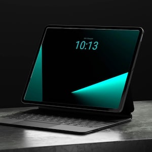 Könnte beinhalten: Ein schwarzes Tablet mit Tastaturaufsatz, das eine Digitaluhr mit der Anzeige 10:13 in türkisfarbenen Ziffern auf einem dunklen Bildschirm mit abstrakten türkisfarbenen geometrischen Formen zeigt. Das Gerät hat einen dünnen Rahmen.