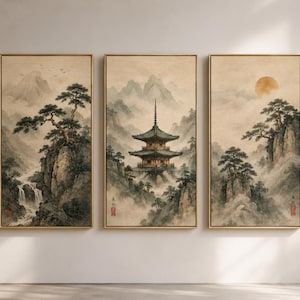 May include: Three framed wall art pieces depicting a serene Asian landscape. The artwork features a pagoda, mountains, trees, and a waterfall, all rendered in muted tones of beige, gray, and green. The frames are gold.