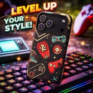 May include: Black phone case with a gaming theme, featuring red, blue, and gold controller graphics. The case has the words "LEVEL UP YOUR STYLE!" in a bold font. The case is on top of a keyboard.