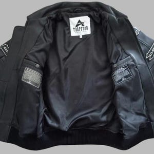 Black Avirex leather jacket featuring bold embroidered Avirex LDN lettering on the back, classic bomber style, ribbed cuffs and hem, premium craftsmanship.