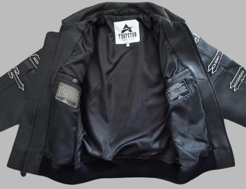 Black Avirex leather jacket featuring bold embroidered Avirex LDN lettering on the back, classic bomber style, ribbed cuffs and hem, premium craftsmanship.