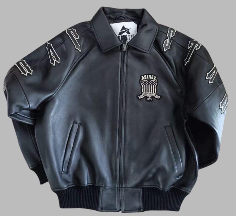 Black Avirex leather jacket featuring bold embroidered Avirex LDN lettering on the back, classic bomber style, ribbed cuffs and hem, premium craftsmanship.