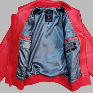 Premium Avirex USA red leather jacket with embroidered logo detailing, classic bomber style, ribbed cuffs and hem, high-quality craftsmanship.