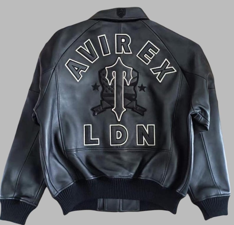Black Avirex leather jacket featuring bold embroidered Avirex LDN lettering on the back, classic bomber style, ribbed cuffs and hem, premium craftsmanship.