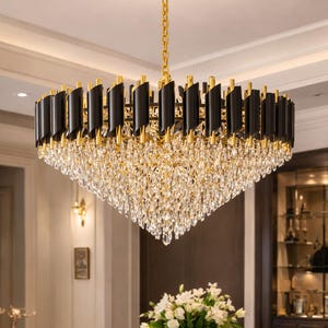 May include: A rectangular chandelier with a gold finish and black accents. The chandelier is suspended from a gold chain and features multiple tiers of crystal pendants, creating a luxurious and elegant lighting fixture.