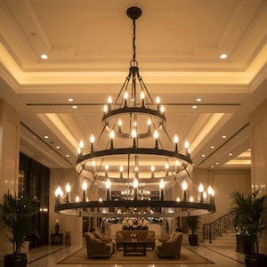 Può includere: Un grande lampadario a più livelli con numerose luci a forma di candela appese al soffitto. Il lampadario ha una struttura in metallo scuro ed è sospeso da una catena. L'immagine è scattata in un elegante spazio interno ben illuminato.