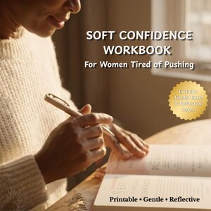 May include: A person writing in a workbook titled "Soft Confidence Workbook." The book is open, with text visible on the pages. The cover text reads "For Women Tired of Pushing." Additional text includes "Printable, Gentle, Reflective."