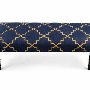 May include: A navy blue bench with a gold geometric pattern on the upholstered top. The bench has four black, turned legs. The design is a classic style, suitable for a living room or hallway.