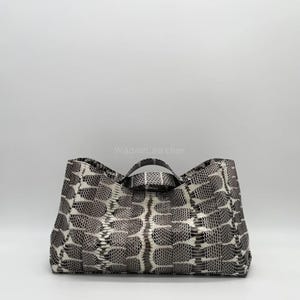 May include: A large tote bag with a snakeskin pattern in grey and white. The bag has two short handles and a rectangular shape. The text "WagneLeather" is visible on the bag.