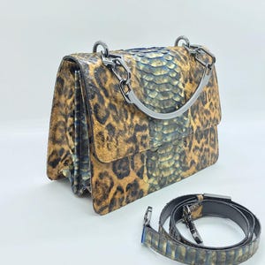 May include: A white ceramic mug with a black handle and the text "But First, Coffee" in a black, handwritten-style font. The mug is on a white surface.