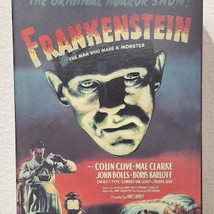 Può includere: Una scatola in stile vintage con il poster del film "Frankenstein". Il poster ha uno sfondo scuro con il titolo del film in grandi lettere stilizzate. L'immagine include un ritratto del mostro e il cast.