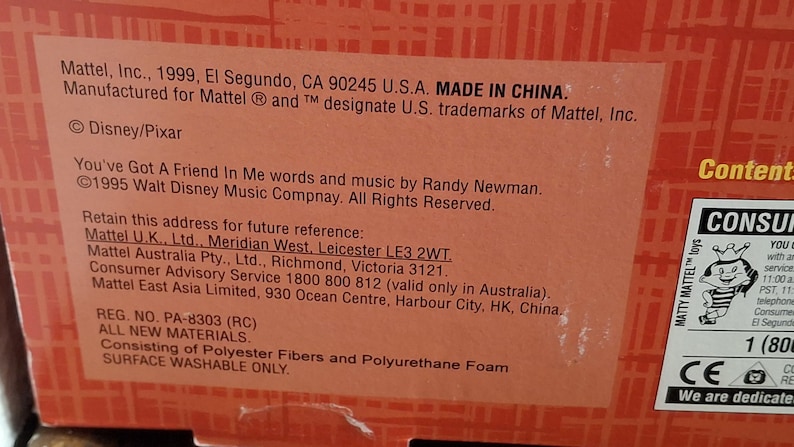 Puede incluir: Primer plano de una caja de producto con texto que incluye "Mattel, Inc., 1999, El Segundo, CA 90245 U.S.A. MADE IN CHINA." La caja tambi&eacute;n presenta el logotipo de Disney/Pixar y texto sobre la canci&oacute;n "You've Got A Friend In Me."