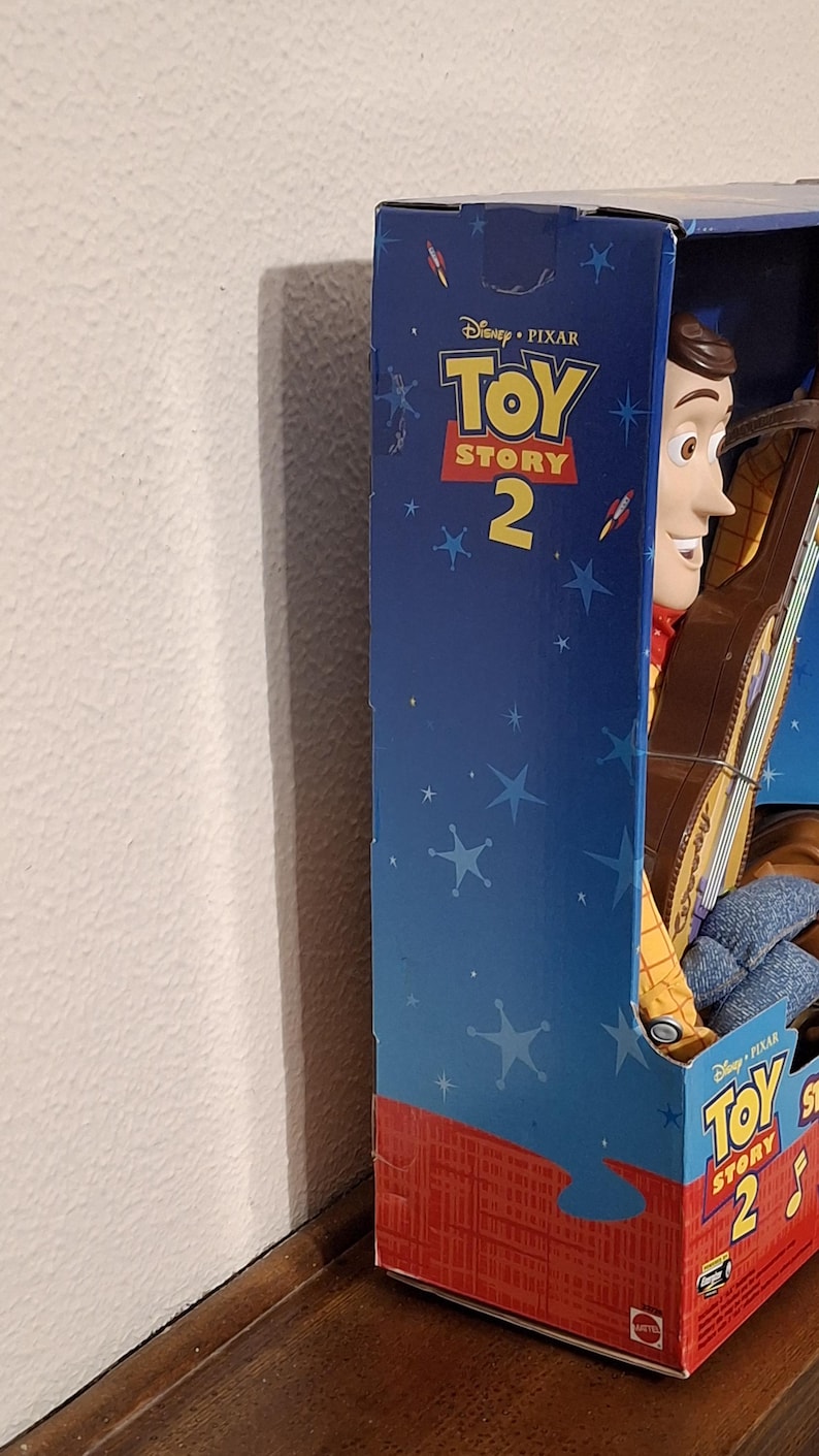 Puede incluir: Figura de acci&oacute;n de Woody de Toy Story 2 en su caja original. La caja azul presenta el logotipo de Disney Pixar Toy Story 2 y gr&aacute;ficos de estrellas. Woody lleva su atuendo de vaquero caracter&iacute;stico.