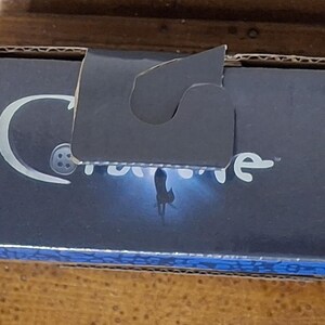 K&ouml;nnte beinhalten: Eine marineblaue Pappschachtel mit wei&szlig;em Logo und dem Wort "Caronline" in wei&szlig;er Schrift. Die Schachtel hat einen Griff und einen blau gemusterten Rand. Die Schachtel befindet sich auf einer Holzoberfl&auml;che.