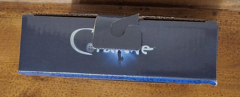 K&ouml;nnte beinhalten: Eine marineblaue Pappschachtel mit wei&szlig;em Logo und dem Wort "Caronline" in wei&szlig;er Schrift. Die Schachtel hat einen Griff und einen blau gemusterten Rand. Die Schachtel befindet sich auf einer Holzoberfl&auml;che.