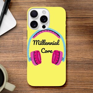 Könnte beinhalten: Gelbe Handyhülle mit einer Grafik von rosa und blauen Kopfhörern und den Worten "Millennial Core". Die Handyhülle hat ein Kameramodul mit drei Objektiven.