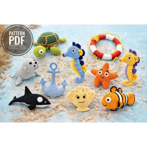 Puede incluir: Una colección de criaturas marinas de ganchillo, que incluye una tortuga, caballitos de mar, una estrella de mar, un pez payaso, una foca, una ballena, un ancla, una concha y un salvavidas. Los juguetes son de varios colores, incluyendo verde, azul, naranja, amarillo y blanco. Incluye el texto "PATTERN PDF ENGLISH".