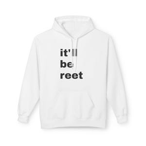 Puede incluir: Sudadera blanca con bolsillo delantero y capucha. La sudadera lleva el texto "it'll be reet" en negro, apilado verticalmente. La sudadera está hecha de un material suave.