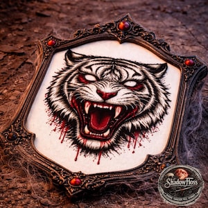 May include: A framed cross-stitch of a snarling tiger with red eyes and blood dripping from its mouth. The ornate frame is dark brown with red accents. The artwork is set against a textured, dark background.