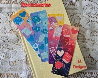 Może przedstawiać: Cztery kolorowe zakładki do książek z tekstem "Romance Trope Bookmarks" i "16 Designs" są wyświetlane na jasnym żółtym książce. Zakładki zawierają różne ilustracje, w tym książki, serca i inne romantyczne elementy.