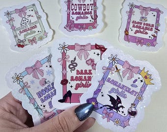 Może przedstawiać: Kolekcja ozdobnych naklejek o tematyce romantycznej. Każda naklejka ma unikalny wzór w różowo-białej ramce, z tekstami takimi jak "Cowboy Romance Girlie" i "Dark Roman Girlie". Naklejki są ozdobione kokardkami i kwiatowymi akcentami.