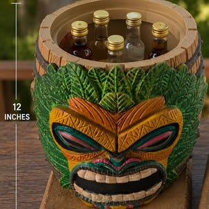 Pode incluir: Um refrigerador em forma de barril com um rosto tiki esculpido em tons de verde, amarelo e laranja. O interior mede 17,78 cm, a altura total é de 30,48 cm e a largura da base é de 20,32 cm. Cinco pequenas garrafas de vidro estão no interior.