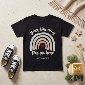 May include: Black t-shirt with a rainbow design and the text "your Winning Design here". The shirt is paired with black canvas sneakers and a green stuffed dinosaur. Wooden star-shaped decorations and a beige blanket are also present.