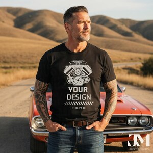 May include: Black t-shirt with a white engine graphic and the text "YOUR DESIGN HERE". The t-shirt is paired with blue jeans and a brown belt. An orange classic car is in the background.